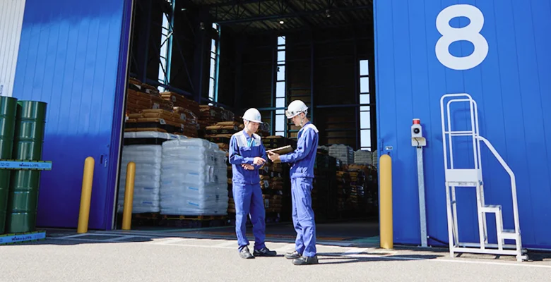 倉庫前で打ち合わせをする2人の作業員